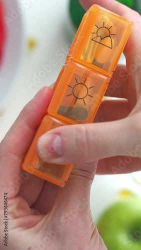Hold a pill box with vitamins in your hand. Sort the tablets and close the container. Daily intake of vitamins and microelements. Biohacking, supplements to improve the body's efficiency