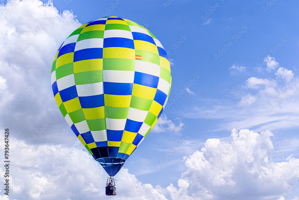 Naklejka premium Colorful hot air balloon flying over blue sky with white clouds 