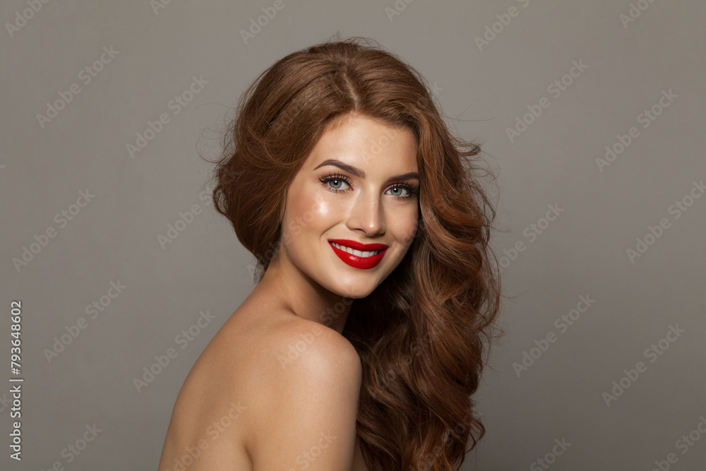 Naklejka premium Joyful young female model with healthy hair, makeup and shiny clear skin posing against gray studio wall background. Facial treatment, cosmetology, hair care and beauty woman concept
