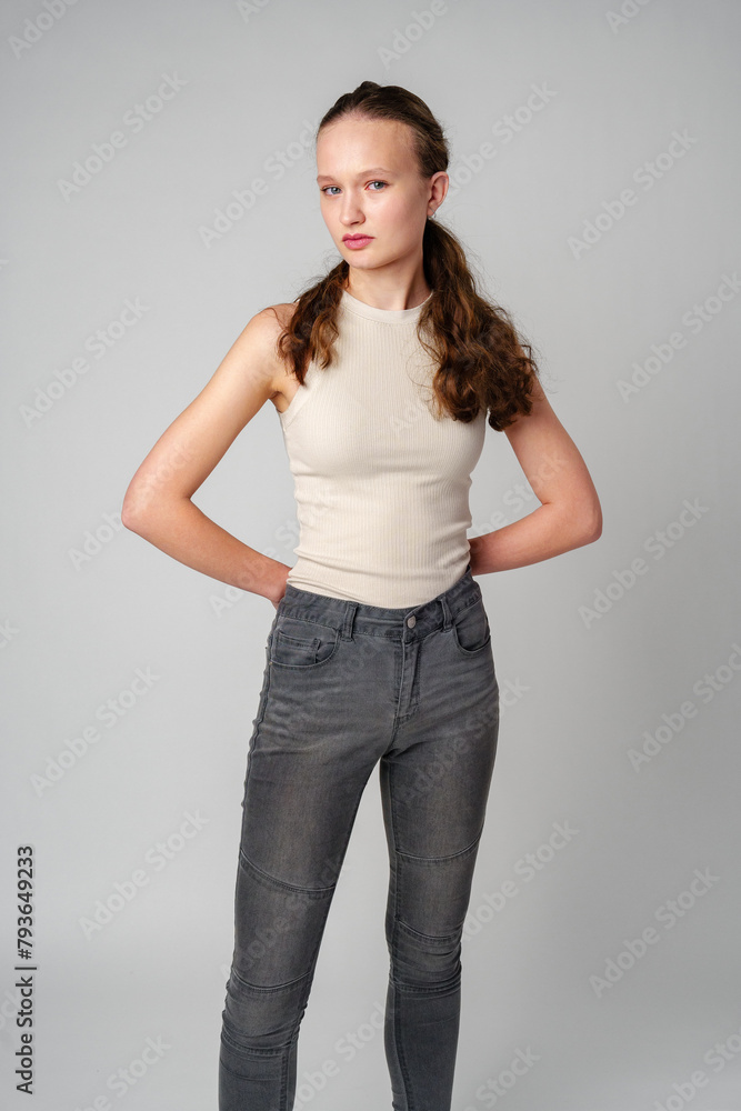 Girl in Beige Tank Top and Grey Jeans on gray background Girl in Beige Tank Top and Grey Jeans on gray background