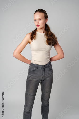 Girl in Beige Tank Top and Grey Jeans on gray background