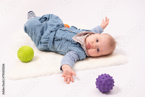 Portrait of a pretty baby girl is plaing with balls