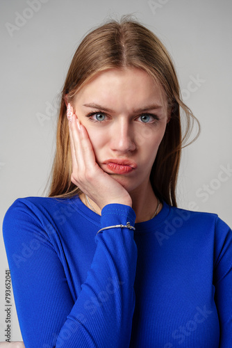 Young Woman In Black Shirt Expressing Discontent Against Grey Background