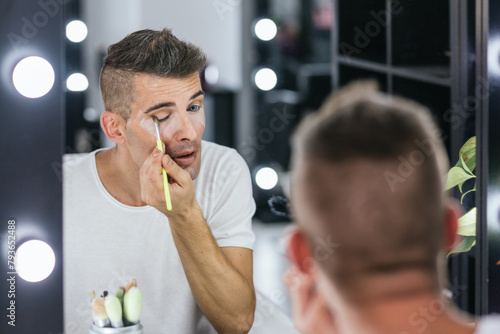 Man applying make-up on face while preparing in the dressing room.