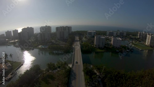 Aerial 4K Drone footage of cars driving over Vanderbilt Channel on Bluebill Avenue leadings to Wiggins Pass Beach, Naples, Florida, USA. Video includes Vanderbilt  Landing Condos and surrounding area. photo