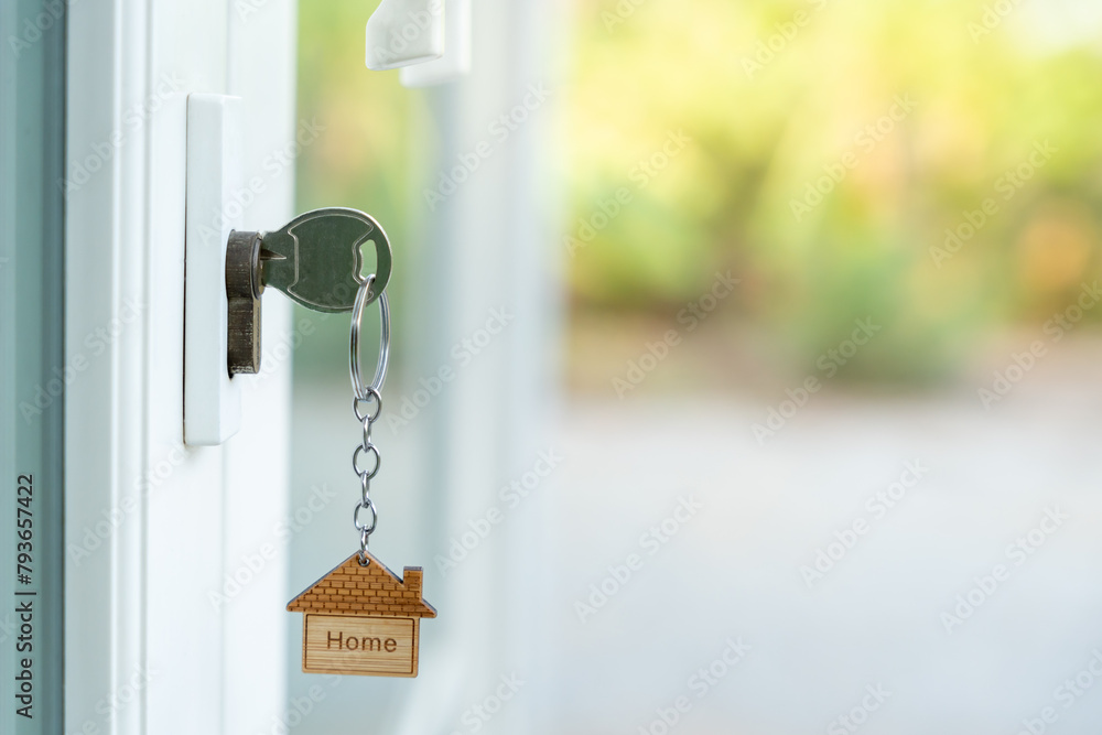 Naklejka premium Landlord key for unlocking house is plugged into the door. Second hand house for rent and sale. keychain is blowing in the wind. mortgage for new home, buy, sell, renovate, investment, owner, estate