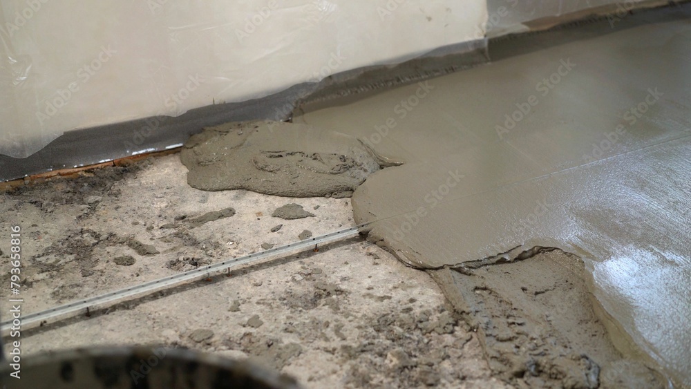 Repair of self-leveling floor in an apartment. Fresh screed on the floor in the apartment, construction work and repairs. Close-up of a freshly poured concrete floor. - obrazy, fototapety, plakaty 