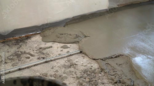 Repair of self-leveling floor in an apartment. Fresh screed on the floor in the apartment, construction work and repairs. Close-up of a freshly poured concrete floor.