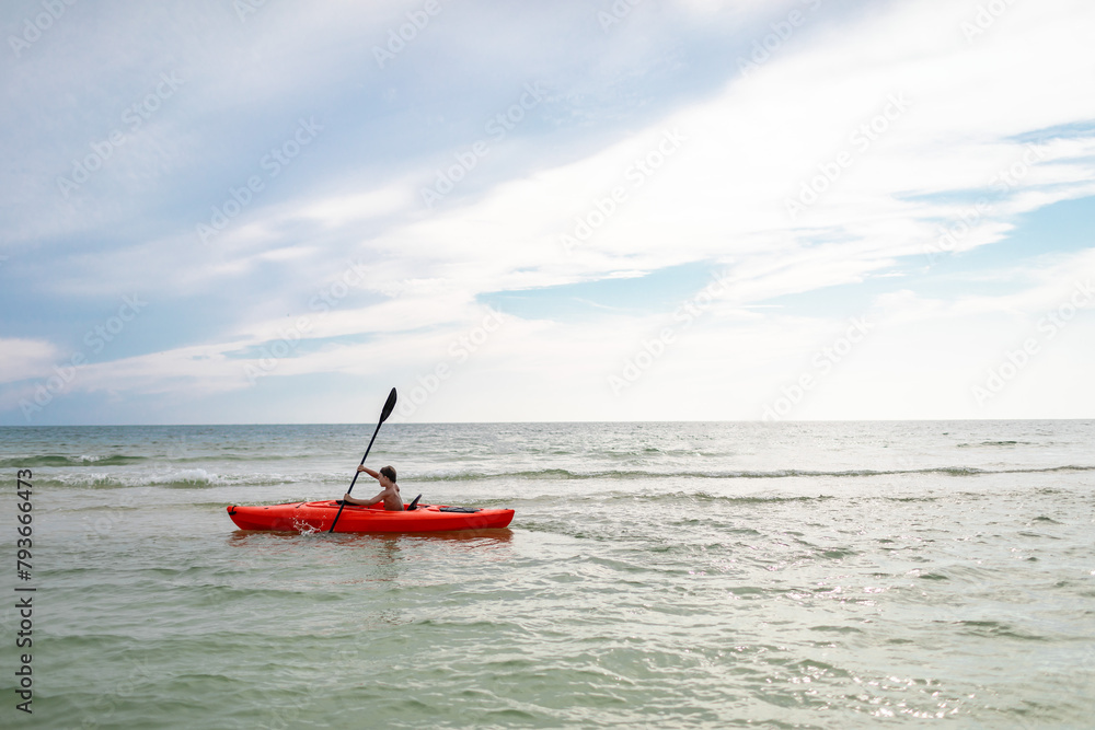 Child paddling in a kayak alone in a serene ocean setting Child paddling in a kayak alone in a serene ocean setting