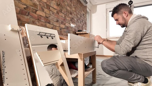 Man working and assembling furniture in a new apartment. photo