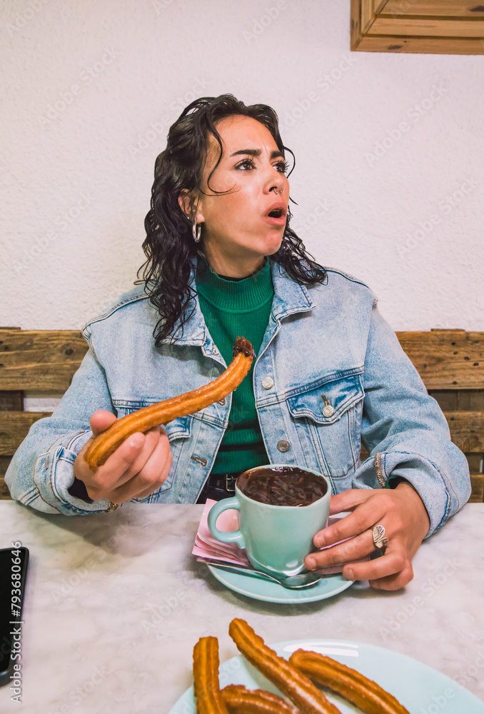 Arab woman caught eating chocolate with churros in Spain. Lifestyle, vertical image. - obrazy, fototapety, plakaty 