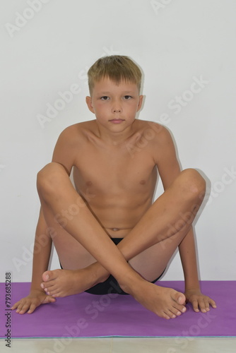 A fair-haired blond man sits in a yoga pose.