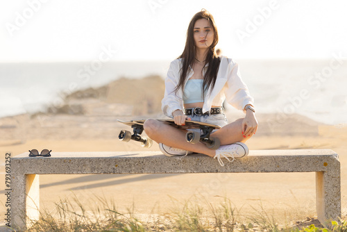 A woman is sitting on a bench with a skateboard in her hand
