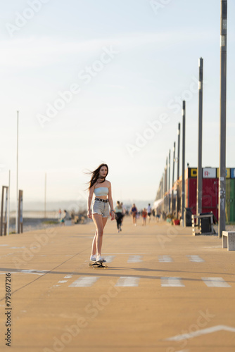 A woman is skateboarding down a sidewalk