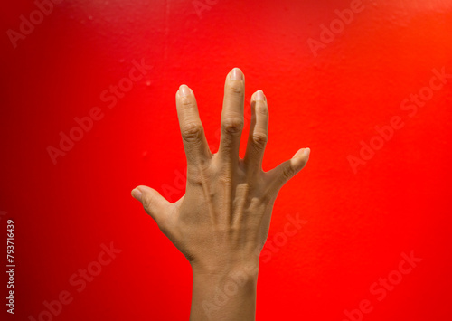 Communicate signs or symbols using sign language on a bright red background.