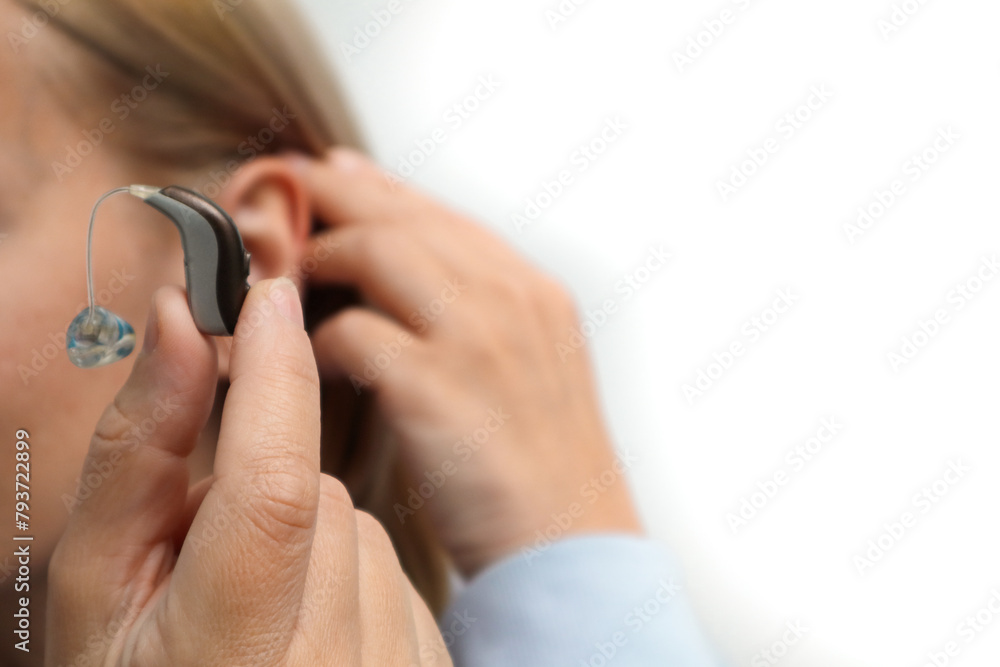 Deaf patient with audiology implant. Close up of woman hand holding digital hearing aid. Unrecognizable woman putting on a modern hearing aid on her ear. Stylish hearing device Deaf patient with audiology implant. Close up of woman hand holding digital hearing aid. Unrecognizable woman putting on a modern hearing aid on her ear. Stylish hearing device