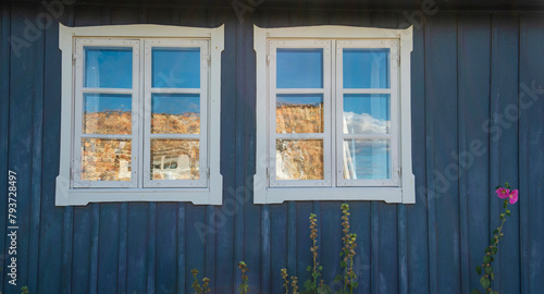 windows with white frame on blue facade and flowers of a typical scandinavian house