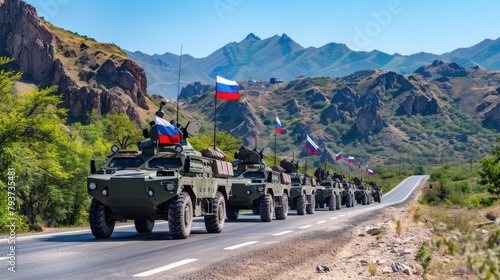 A line of Russian military vehicles with flags on them are driving along an asphalt road at full height, against which there is rocky terrain and mountains in the background. photo