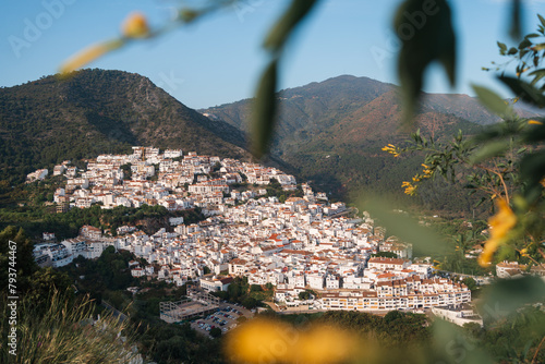 Warm evening light bathes the white village of Ojen, Spain, nestled in the lush mountains of Andalusia