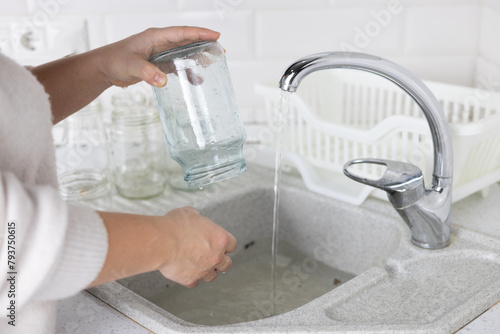 Close-up of a woman's hands washing a glass jar for recycling. A woman collects unwanted glassware and sends it for recycling. The concept of environmentally friendly use of materials.