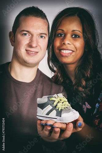 Happy multiracial couple holding a baby shoe