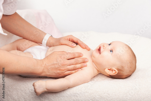 Gentle baby chest massage by a caregiver on a soft white blanket