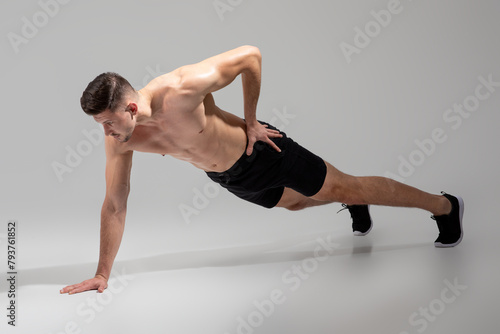 Man Performing One-Arm Push Up On Grey
