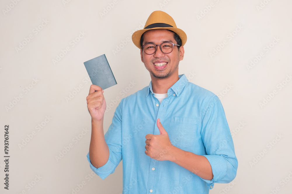 A man smiling at the camera and give thumbs up while holding passport document