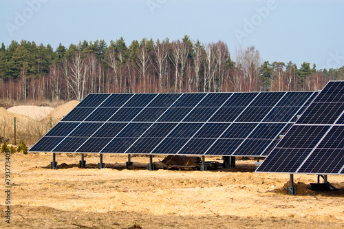 solar panels close up, green forest and blue sky in the background