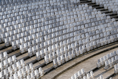 White seats in rows in empty amphitheatre auditorium outdoors. Empty seats in outdoor concert hall
