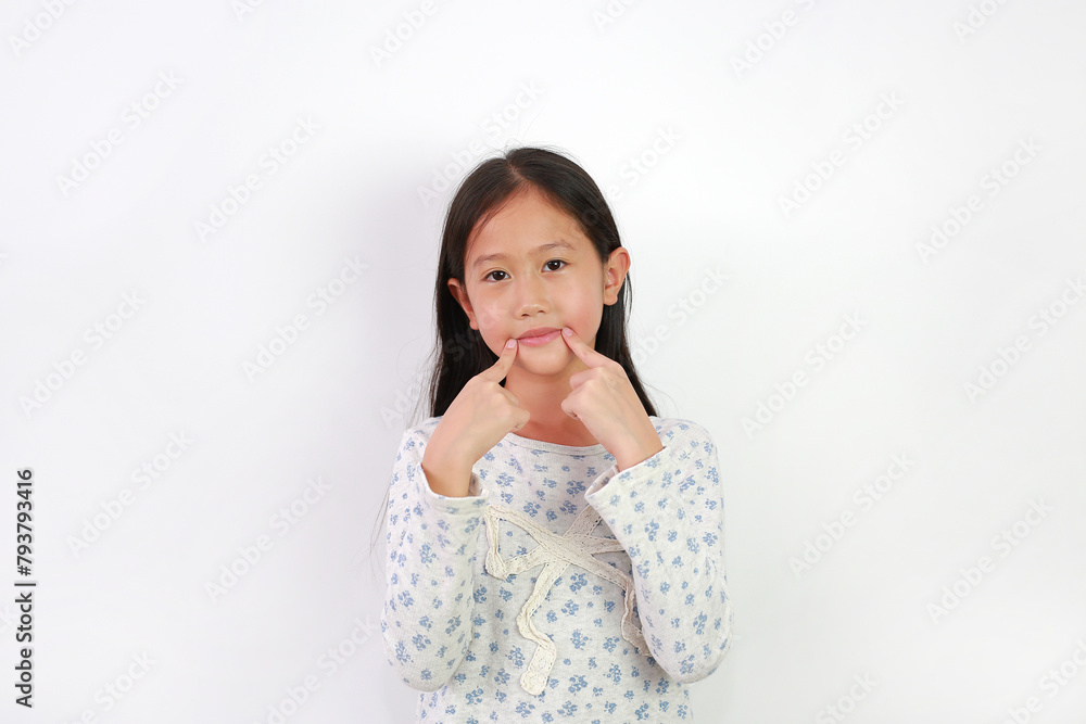 Portrait of young Asian girl child keeping fingers on corner of mouth isolated on white background. Child point at the part of body. Portrait of young Asian girl child keeping fingers on corner of mouth isolated on white background. Child point at the part of body.