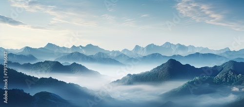 Mountains wrapped in mist under a blue sky