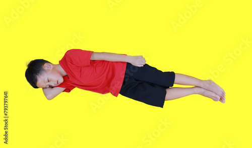 Sleeping Asian boy with arm support his head isolated on yellow background. Full length.