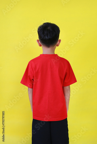 Rear view of Asian boy age 6 year old isolated on yellow background.