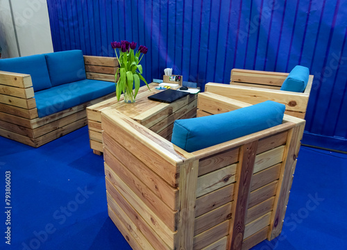 Wooden furniture from pallets in the office interior. Armchairs and coffee table on a blue background.