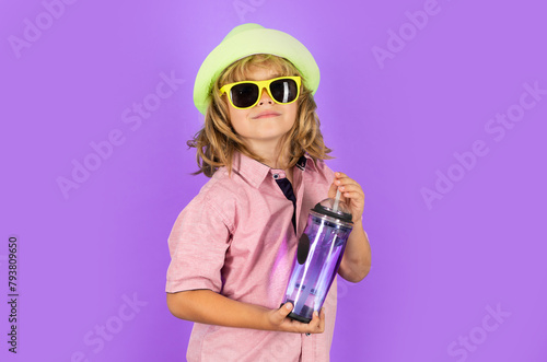 Kid drinking water, isolated on studio background. Portrait of happy smiling little child with glass of fresh water. Thirsty kid. Refreshing. Water balance. Portrait of kid drinking pure still water.