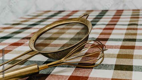 Golden colander and kitchen rod on the table