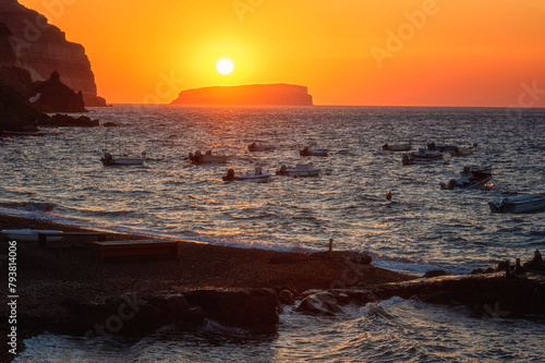 Amazing sunset seascape on Santorini island, scenic view of the Aegean sea, colored sky with sun and volcanic cliffs, Akrotiri beach, Cyclades, Greece. Outdoor travel background, summer holidays