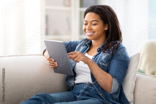 Pretty Woman Sitting on Couch Looking at Tablet