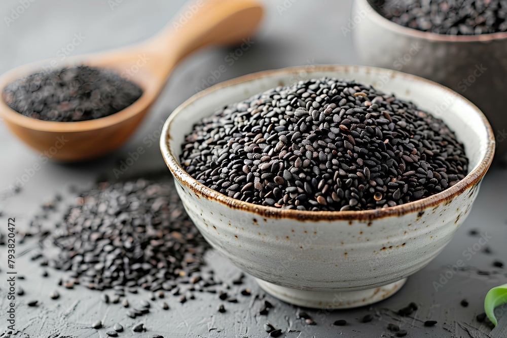 A bowl filled with black rice next to two wooden spoons A bowl filled with black rice next to two wooden spoons