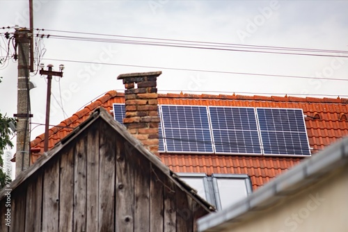 Solar battery on the roof of a house against the background of an old chimney and an old wooden roof