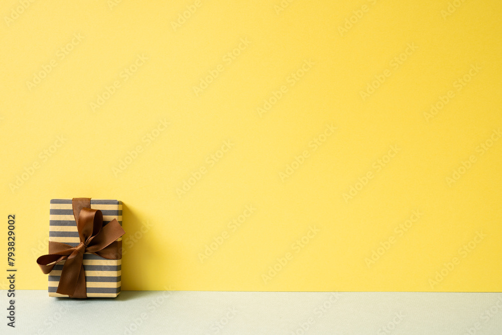 Stripe pattern kraft paper gift box on gray table. yellow wall background. copy space