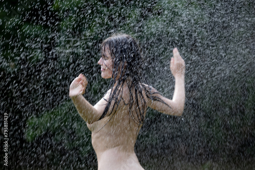 Beautiful woman enjoying under a water jet with thousands of drops in the background