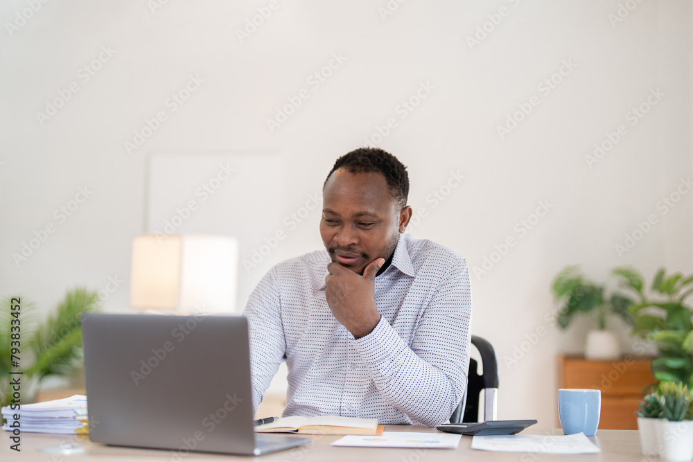 African American businessman working with laptop Take notes on documents in the office and prepare performance analysis reports. African American businessman working with laptop Take notes on documents in the office and prepare performance analysis reports.