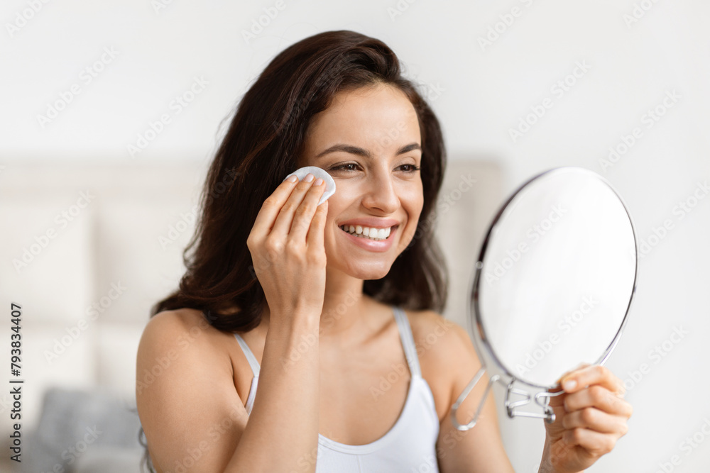 Joyful woman with skincare cotton pad and mirror Joyful woman with skincare cotton pad and mirror