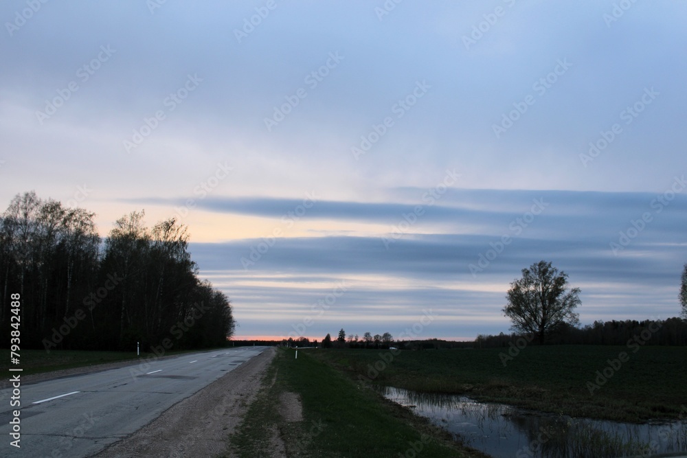 a straight road in the evening hour with a beautiful sky in the background in spring