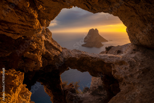 Es Vedra islet view through the rock holes of a cave at sunset  Sant Josep de Sa Talaia  Ibiza  Balearic Islands  Spain