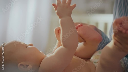 Close-up of a Caucasian baby lying on his back and playing with his mother's fingers. A happy mother watches her newborn baby, who carefully examines her hand. Motherhood concept. Parenthood photo