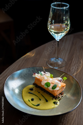 Exquisite salmon delicacy on a gourmet plating, paired with a crisp white wine. Experience fine dining with every bite and sip. (ID: 793850837)