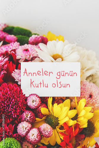 vertical photo of a bright beautiful bouquet of multicolored flowers, white greeting card with the text Happy Mother's Day in Turkish language, mother's day concept. photo